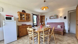 A compact kitchen with a dining table, chairs, a microwave, wooden cabinets, and a hanging light fixture. - 3-room apartment in Flumet - Parking - 6 people (Flumet)