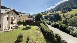 A two-story building with a balcony, surrounded by a well-maintained lawn and a road leading to a hilly landscape. - 3-room apartment in Flumet - Parking - 6 people (Flumet)