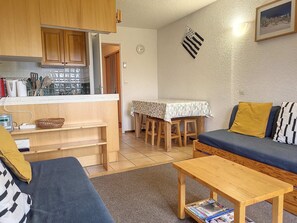 A compact living space with a kitchenette, a dining area, and a seating area with a sofa and a table. - Cozy Apartment Near Slopes with Balconies (Montvalezan-La Rosière)