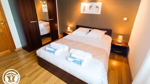 A hotel room with a large bed, a wardrobe, bedside lamps, and a wall-mounted artwork. - La Petite Fagette (Frayssinet-le-Gélat)