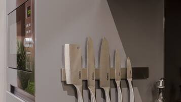 A modern kitchen with a built-in oven, a stovetop, and a knife rack on the wall.