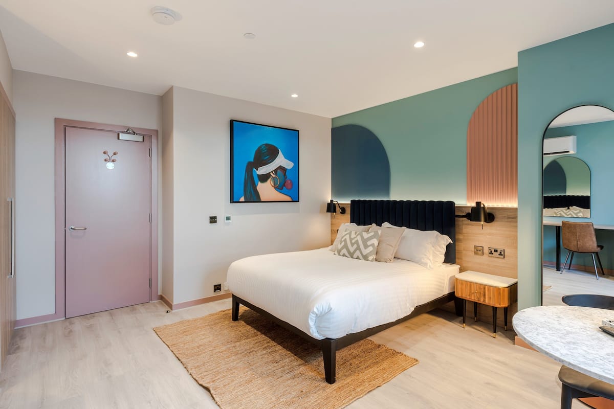 Une chambre moderne avec un grand lit, des tables de chevet, un petit coin salon et une table à manger.