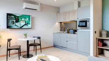 A modern apartment with a kitchen, dining area, and a flat-screen TV mounted on the wall.