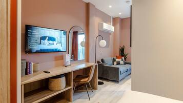 Una sala de estar moderna con un escritorio de madera, un sofá gris y un televisor de pantalla plana montado en la pared.
