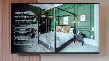 A bedroom with a four-poster bed, a nightstand, a lamp, and a green wall.