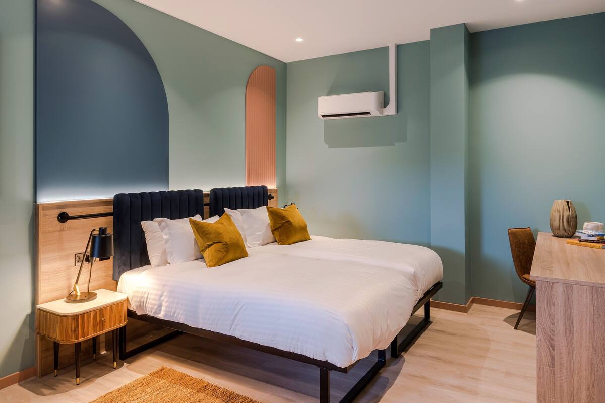 Une chambre moderne avec un grand lit, des tables de chevet, un bureau et un appareil de climatisation.