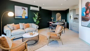 A modern living room with a sofa, chairs, a coffee table, and artwork on the walls.
