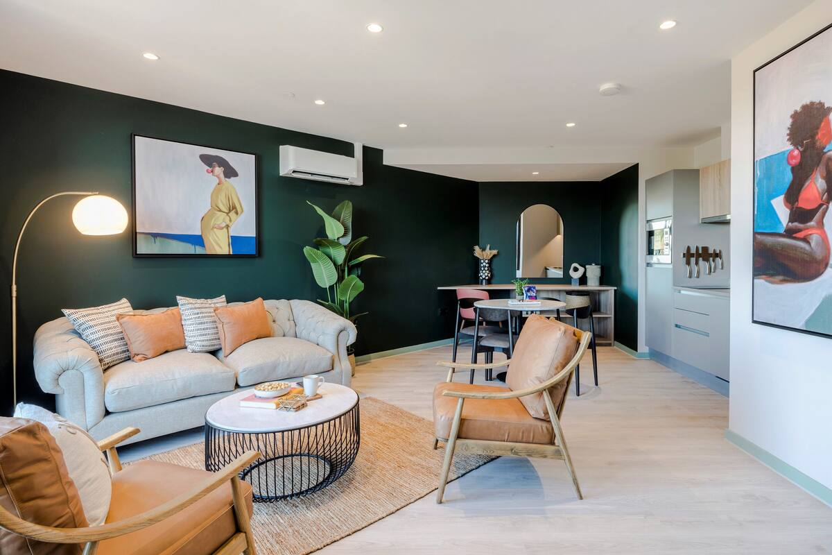 Un salon moderne avec un canapé, des fauteuils, une table basse et des œuvres d’art accrochées aux murs.