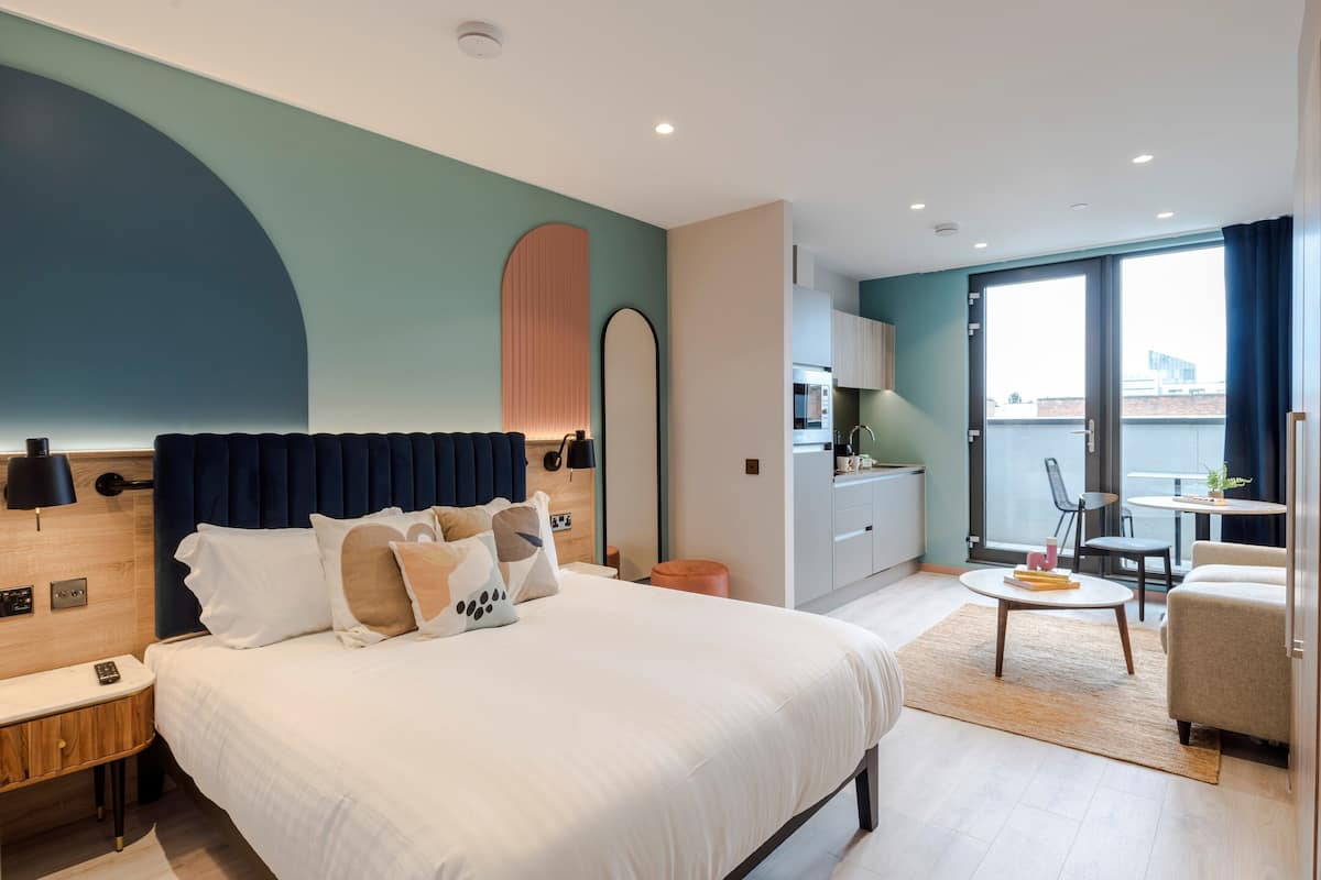 Une chambre d’hôtel moderne, dotée d’un grand lit, d’un bureau et d’un coin repas.