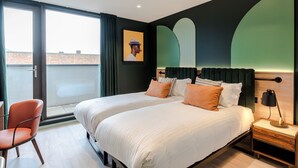 A modern hotel room with two beds, a chair, a nightstand, and a large window offering a city view.