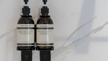 Deux flacons d’après-shampoing et de soin pour le corps, posés sur une surface en marbre.