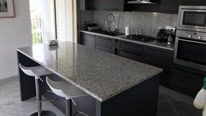 Una cuina moderna amb armaris foscos, taulell de granat i forn d'acer inoxidable, a més d'un microones integrat.
