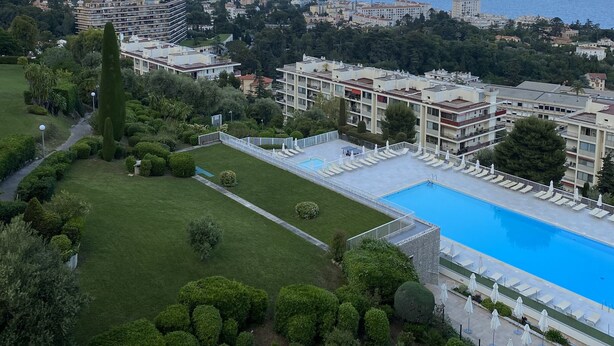 Un hotel amb piscina, envoltat de jardins ben cuidats i vistes al mar.