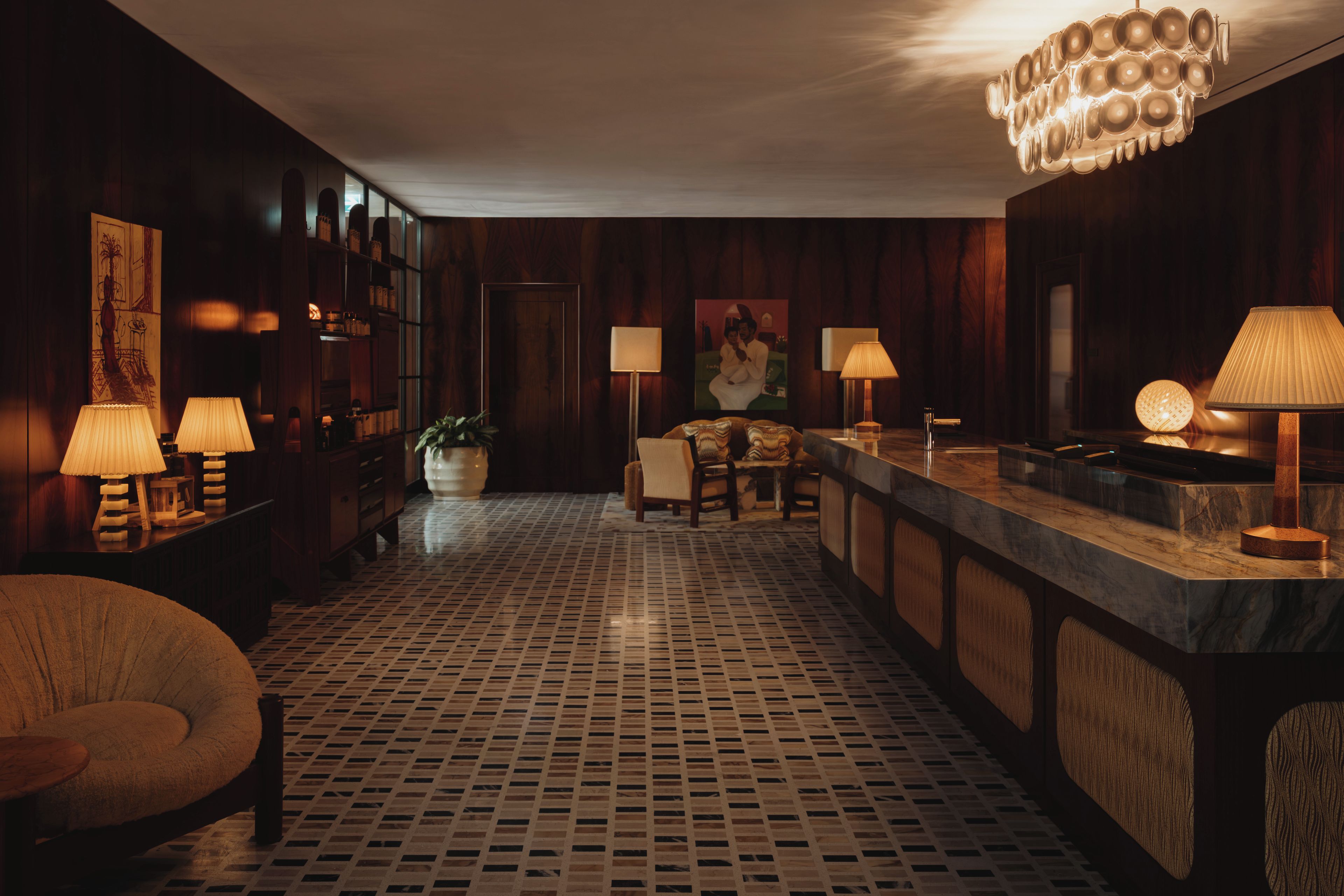 Um saguão de hotel com área de bar, assentos e piso estampado.