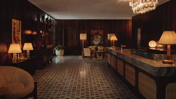 Um saguão de hotel com área de bar, assentos e piso estampado.