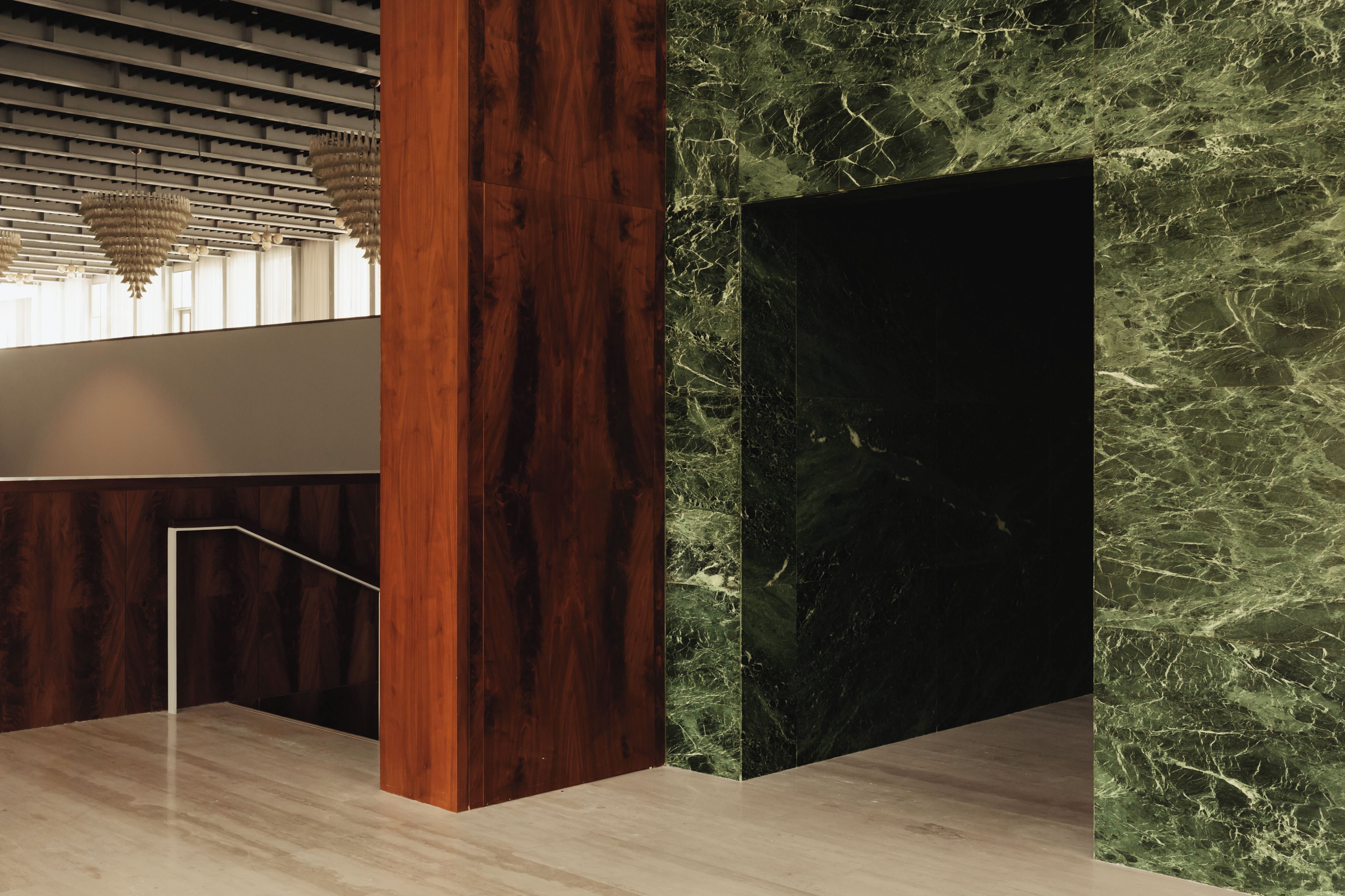 Een modern interieur met een houten kolom, een marmeren wand en een hanglamp.