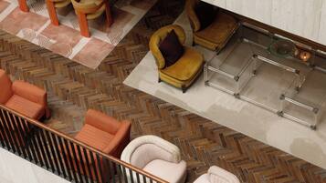 A modern interior with a herringbone floor pattern, a glass coffee table, and a seating area with orange and white chairs.