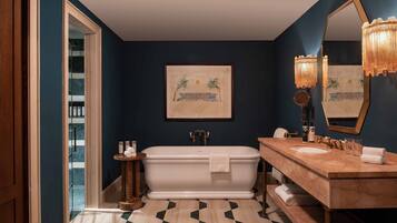 Un baño con una bañera independiente, un tocador con lavabo y un espejo grande.
