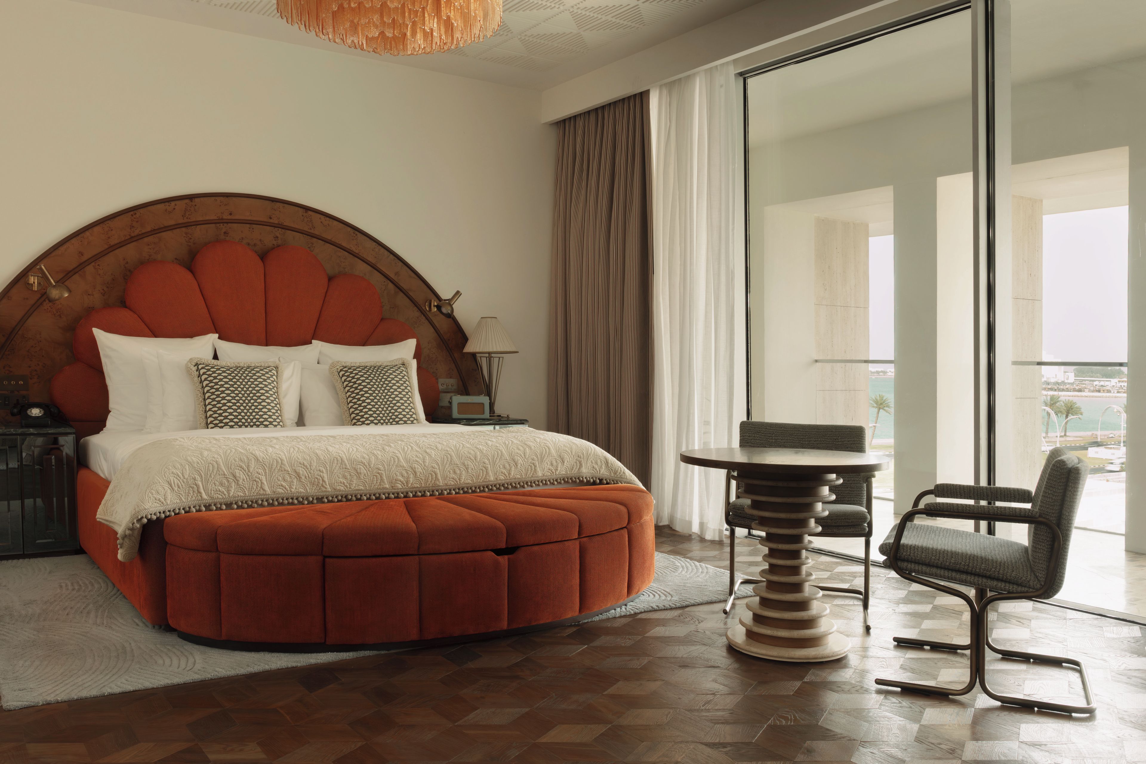 Een slaapkamer met een groot bed, een stoel, een tafel en uitzicht op de omgeving.