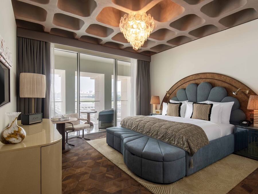 Un dormitorio moderno con una cama grande, una araña, un escritorio y vistas a la ciudad.