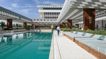 Una piscina al aire libre, sillones reclinables de piscina