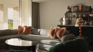 Een moderne woonkamer met een gestreepte bank, een ronde salontafel en een dressoir met planken.