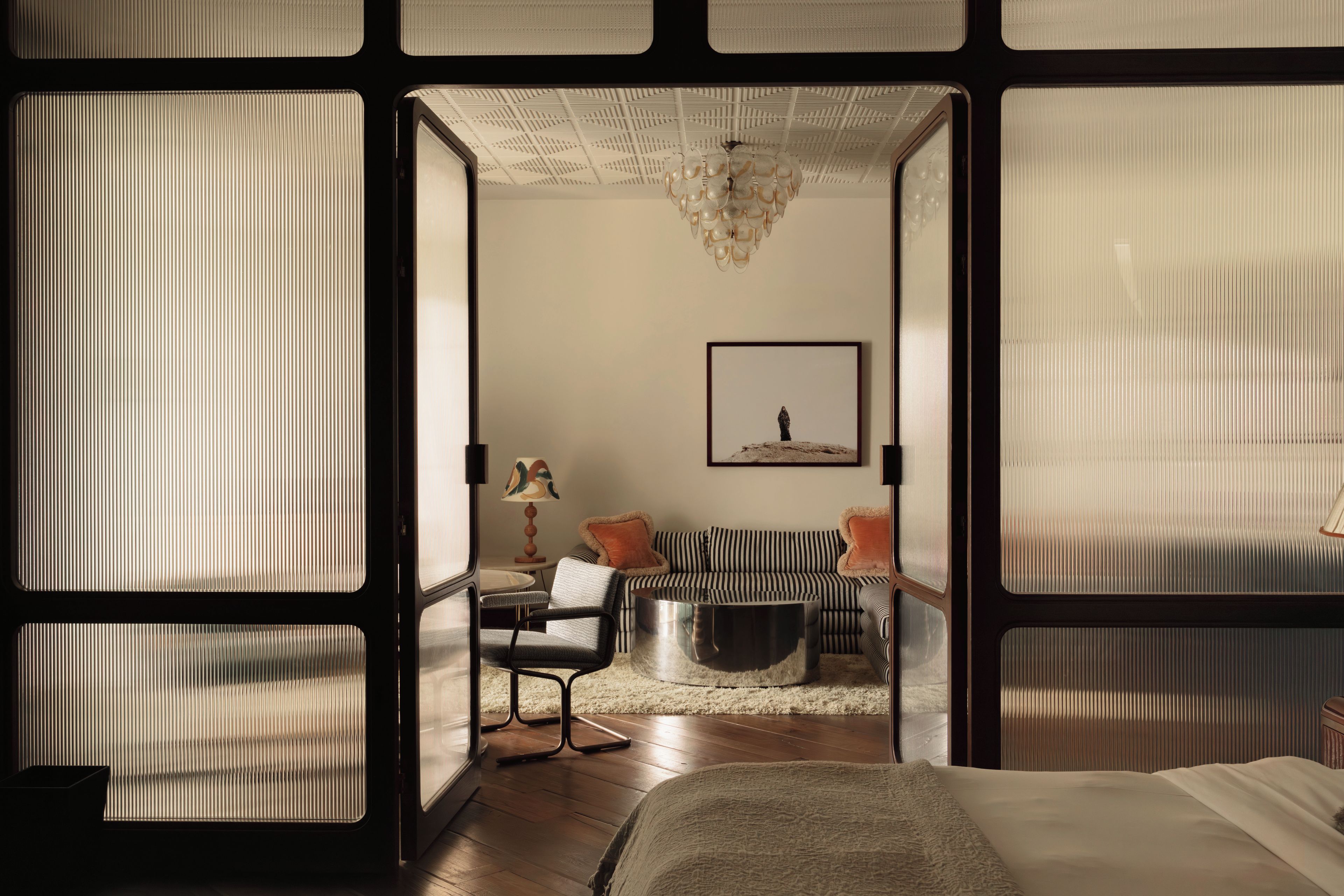 Una habitación con cama, sofá, sillón, mesa y un cuadro en la pared.