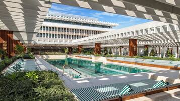 Una piscina al aire libre, sillones reclinables de piscina