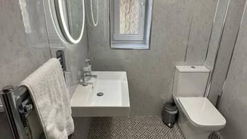 Ein Badezimmer mit Toilette, Waschbecken und einem Fenster.