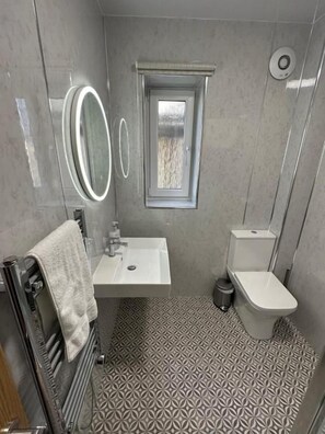 A bathroom with a toilet, sink, and a window. - Royal Oak Guest House (Kirkwall)