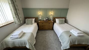 Un dormitorio doble con dos camas individuales, una mesita de noche de madera y un espejo.