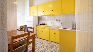 Une cuisine avec des meubles de couleur jaune, une table à manger en bois et un réfrigérateur blanc.