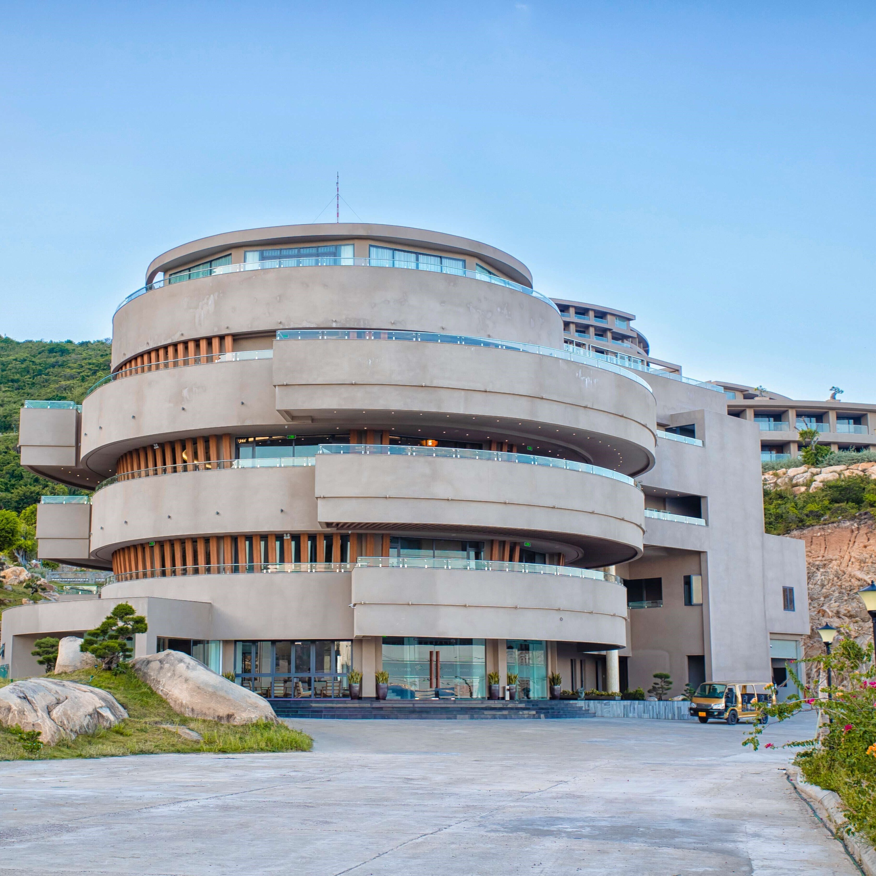 A multi-story building with a circular design, featuring balconies and large windows.