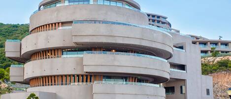 A multi-story building with a circular design, featuring balconies and large windows.