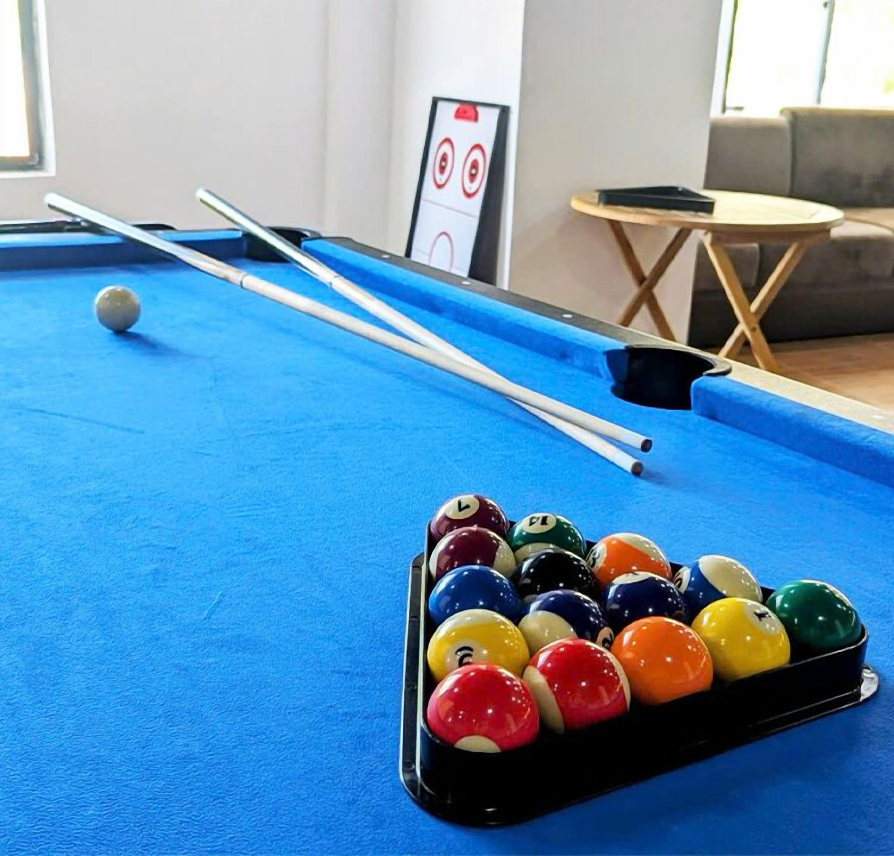 A pool table with a set of billiard balls and two pool cues.