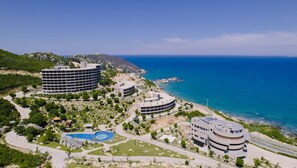 A coastal hotel with multiple buildings, a swimming pool, and a view of the sea. - Ohana Village (Cat Tien)