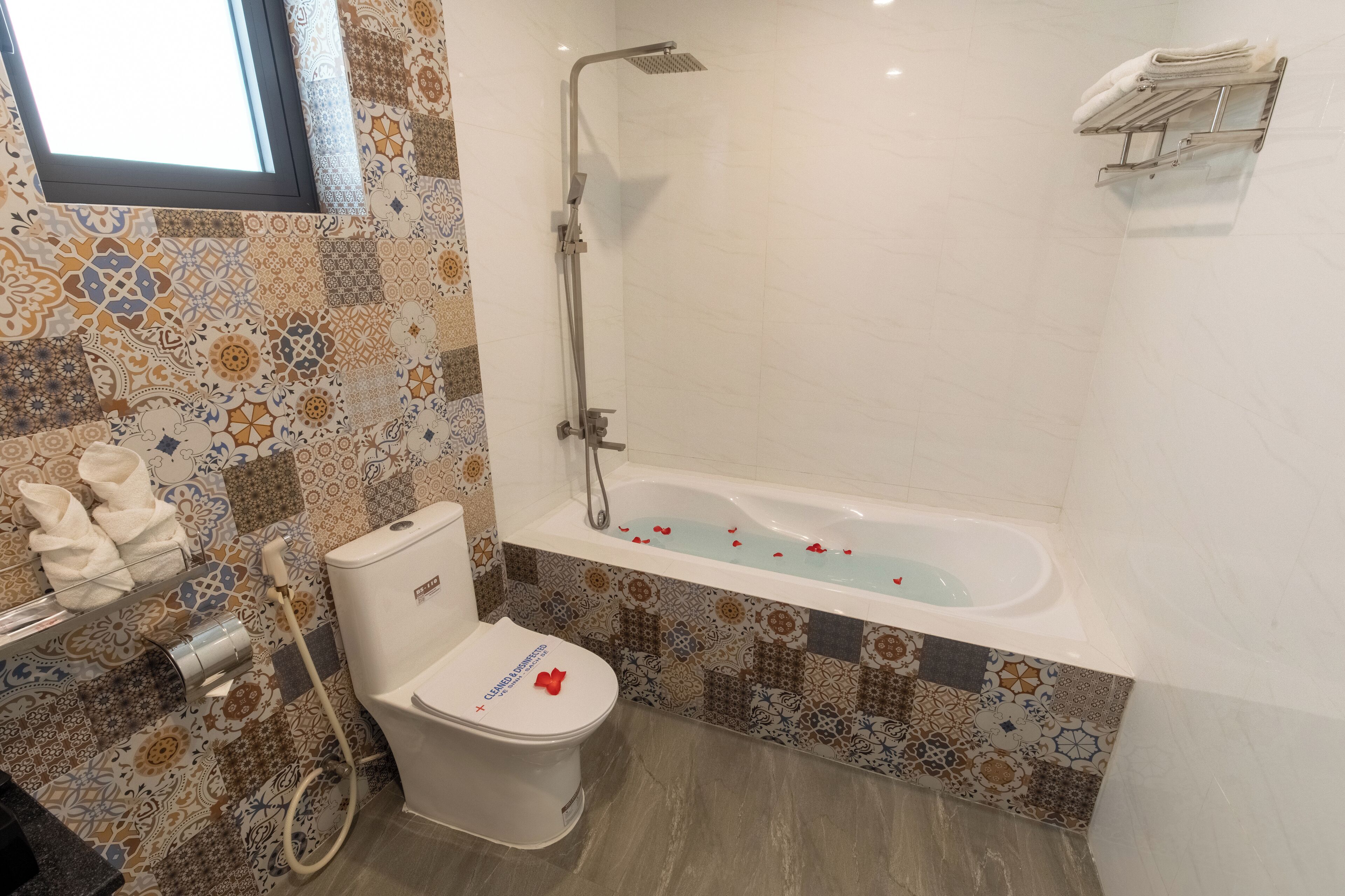 A bathroom with a shower, toilet, and patterned tiles.