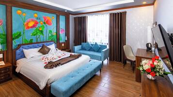 A hotel room with a large bed, a sofa, a desk, and a TV.