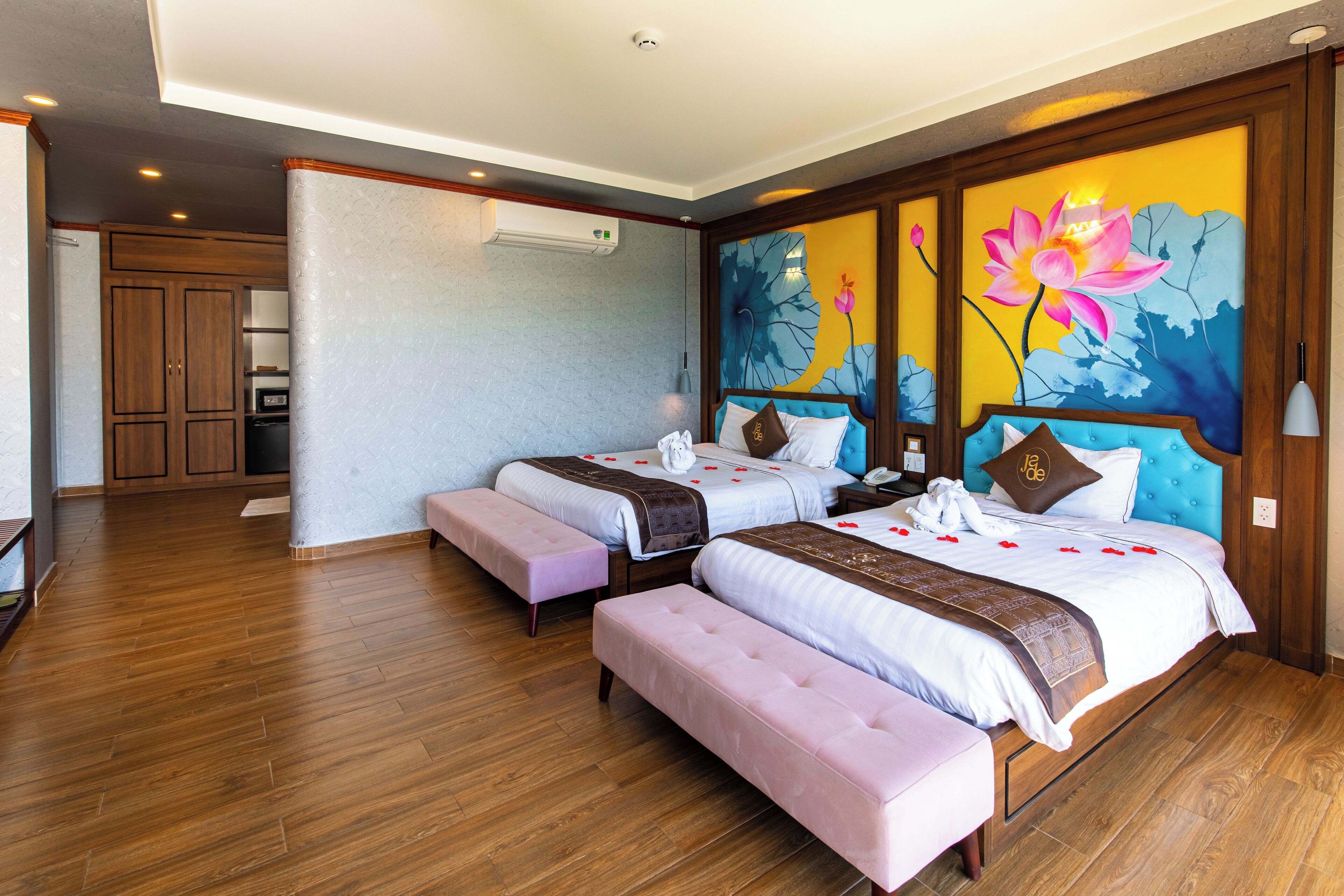 Ein Hotelzimmer mit zwei Betten, einer großen Blumenmalerei, Holzböden und einer Küchenzeile im Hintergrund.