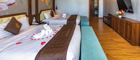 A hotel room with two beds, a bench, a TV, and a wooden cabinet.