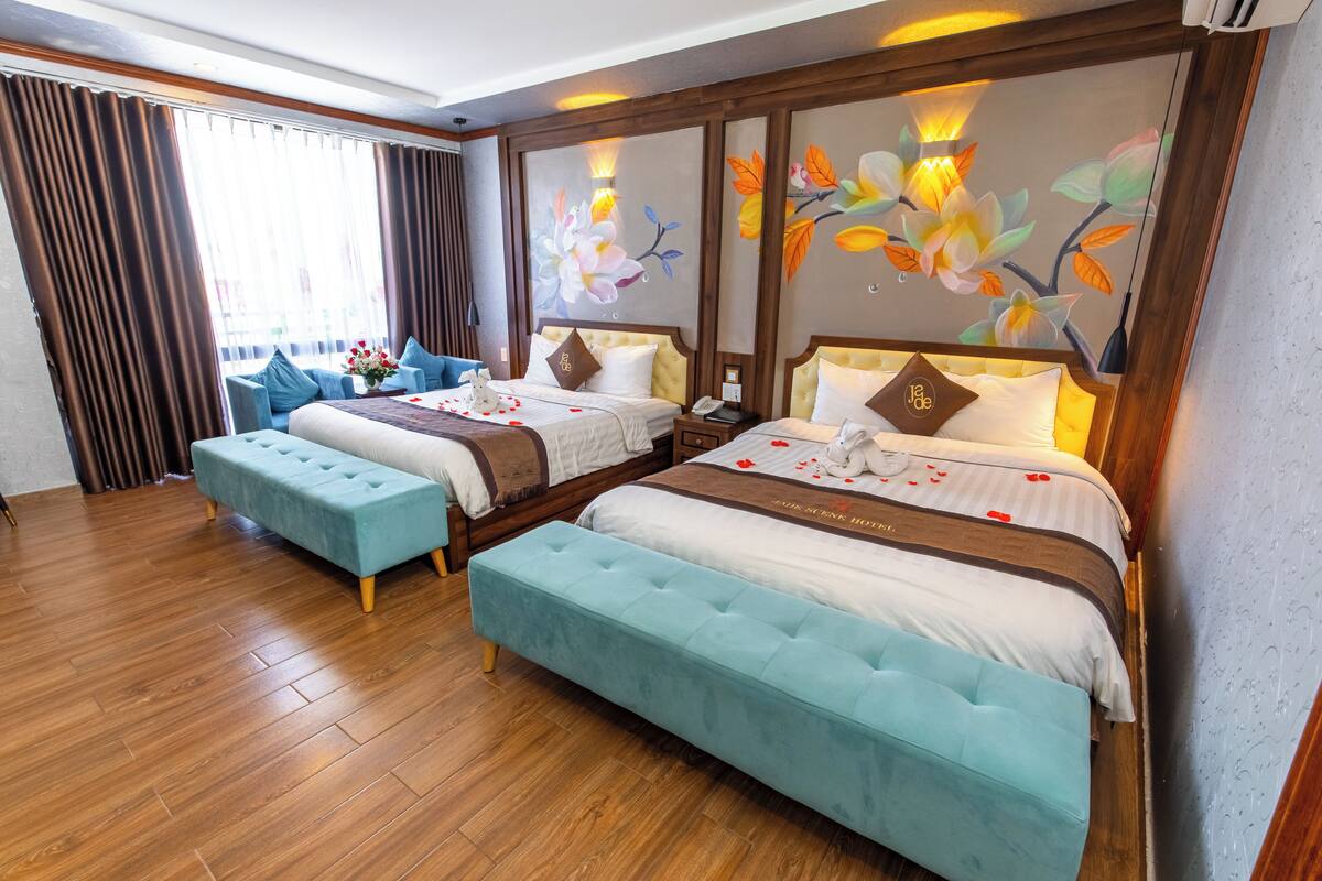 A hotel room with two beds, a wooden floor, and a large window with curtains.
