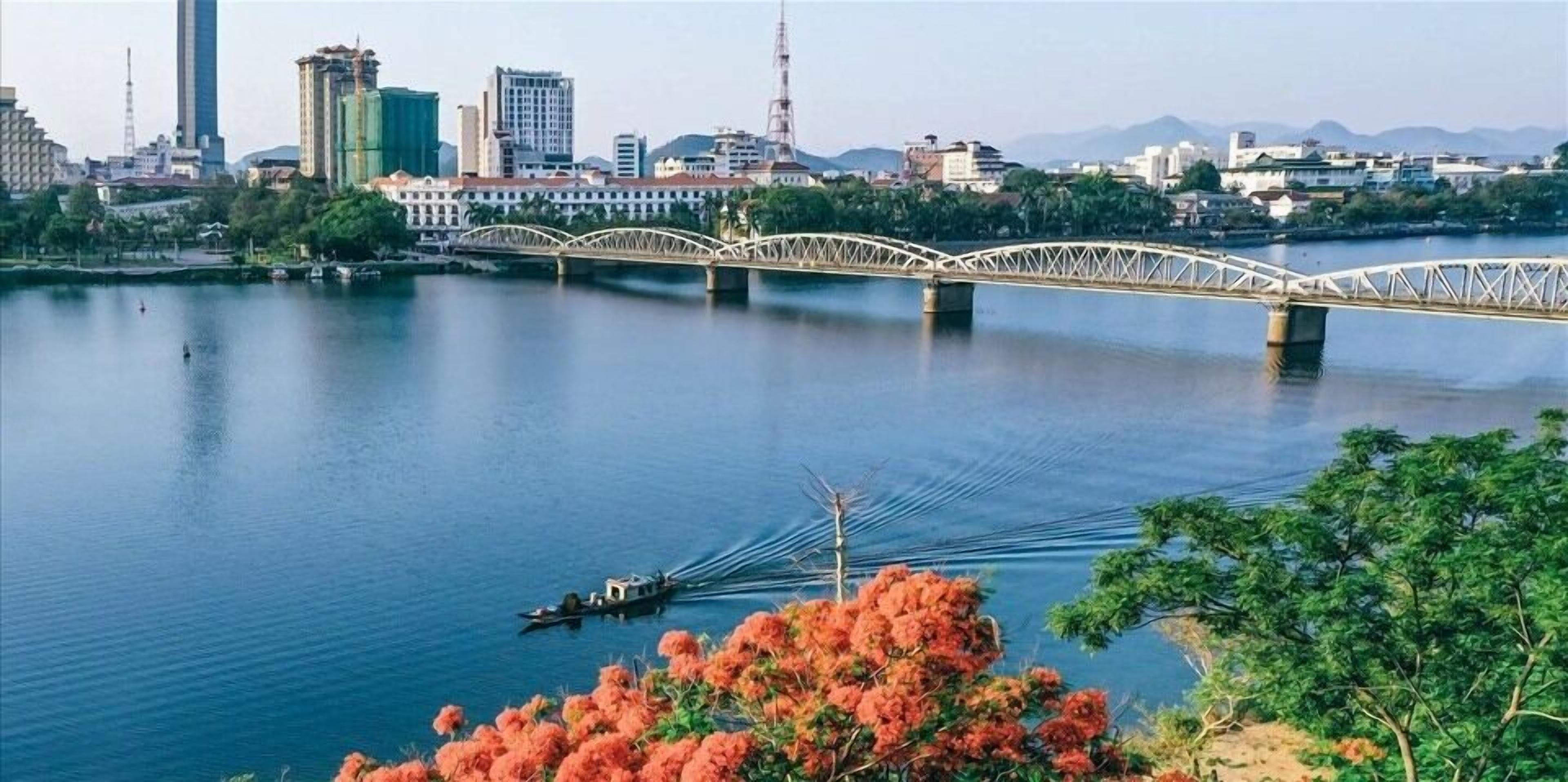 A river with a bridge, boats, and a cityscape in the background.