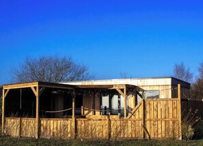 Situated in a serene natural setting, this cabin features a simple, open design with large windows and a flat roof.