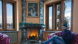 A cozy room with a stone fireplace, red leather sofas, and a glass coffee table with a chessboard. - Hotel Skilift (Frabosa Soprana)