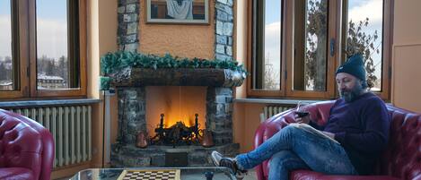 A cozy room with a stone fireplace, red leather sofas, and a glass coffee table with a chessboard.