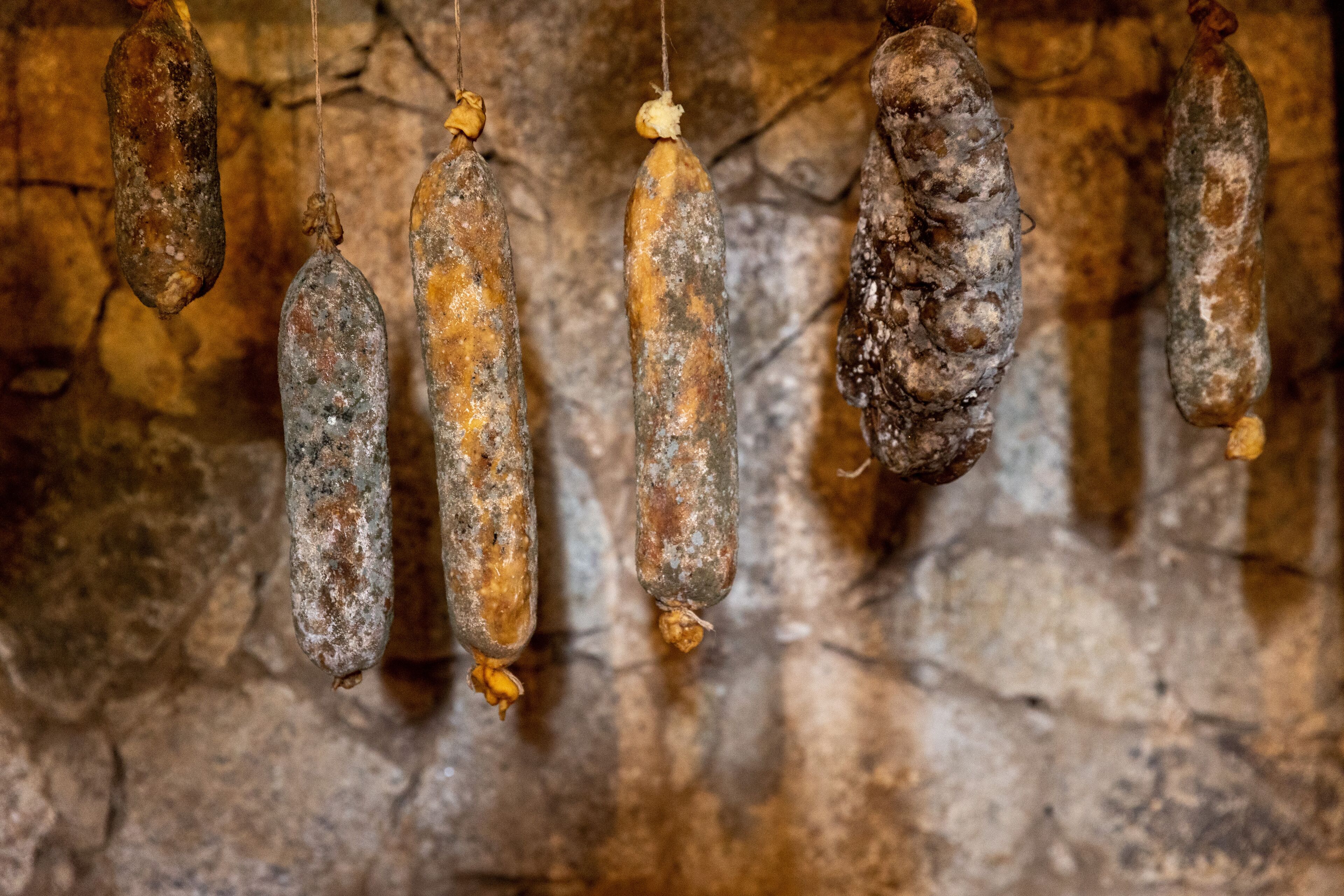 Paredes de pedra com vários objetos pendurados que parecem antigos e possivelmente de madeira ou couro.