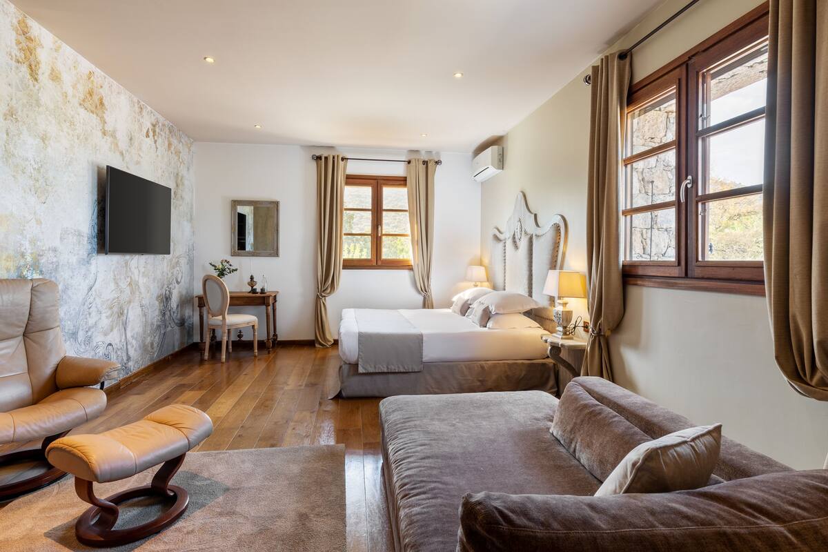 Ein Hotelzimmer mit einem Bett, zwei Sofas, einem Sessel, einem Schreibtisch und einem Fernseher.