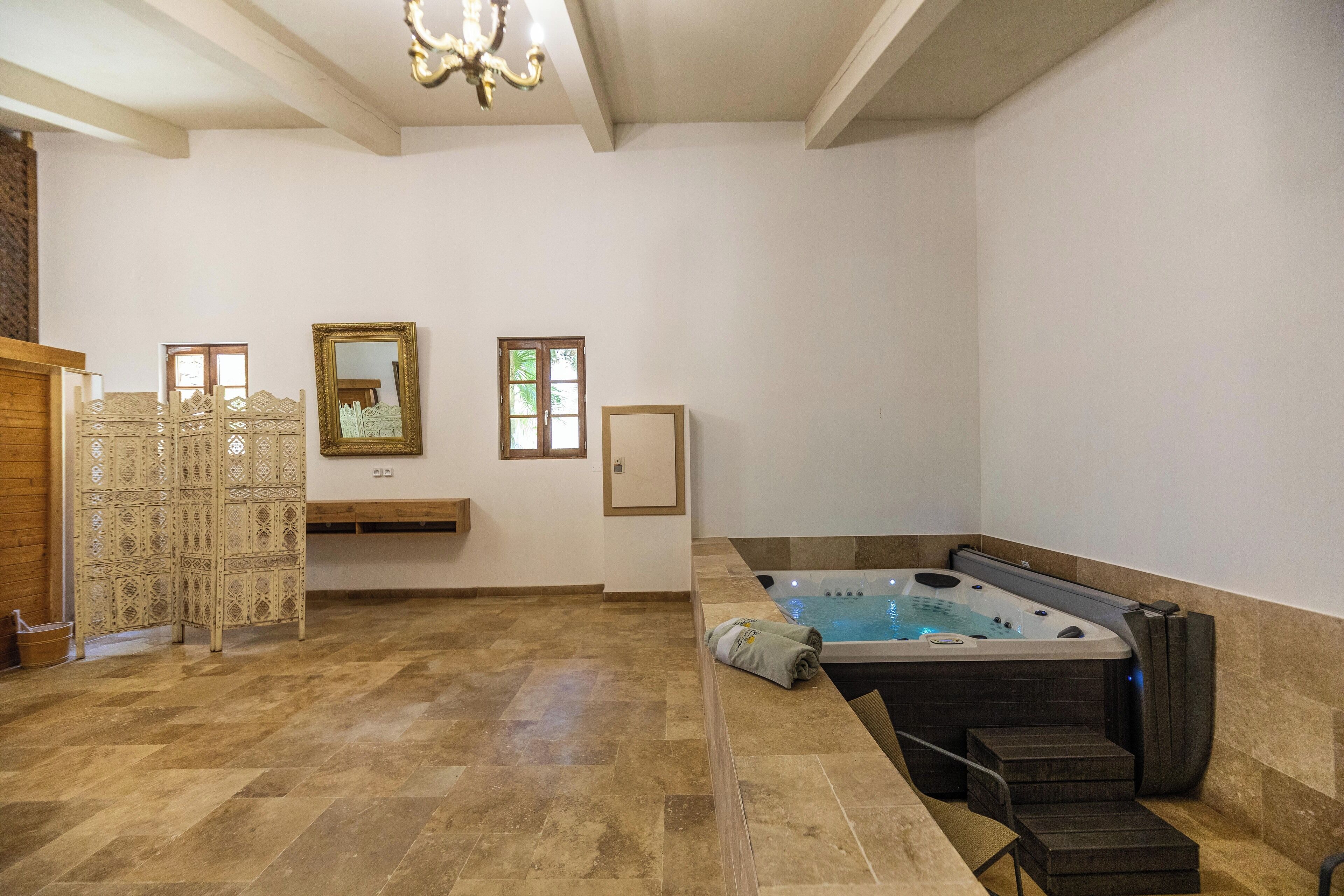 A spacious room with a hot tub, a decorative screen, and a wooden bench.