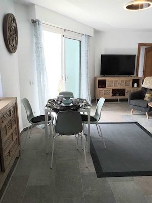 Un salon moderne comprenant un coin repas, un téléviseur à écran plat et un canapé.