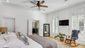 Una camera da letto con un letto, un ventilatore a soffitto, una TV e una poltrona a dondolo.